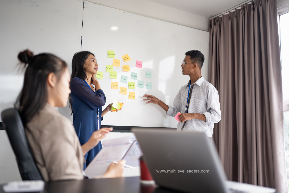 Three colleagues working with sticky notes on a whiteboard to make training stick for a change initiative