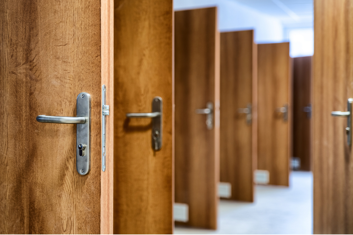 Row of open wooden doors representing the competing priorities and choices senior leaders weigh in consequential decisions.