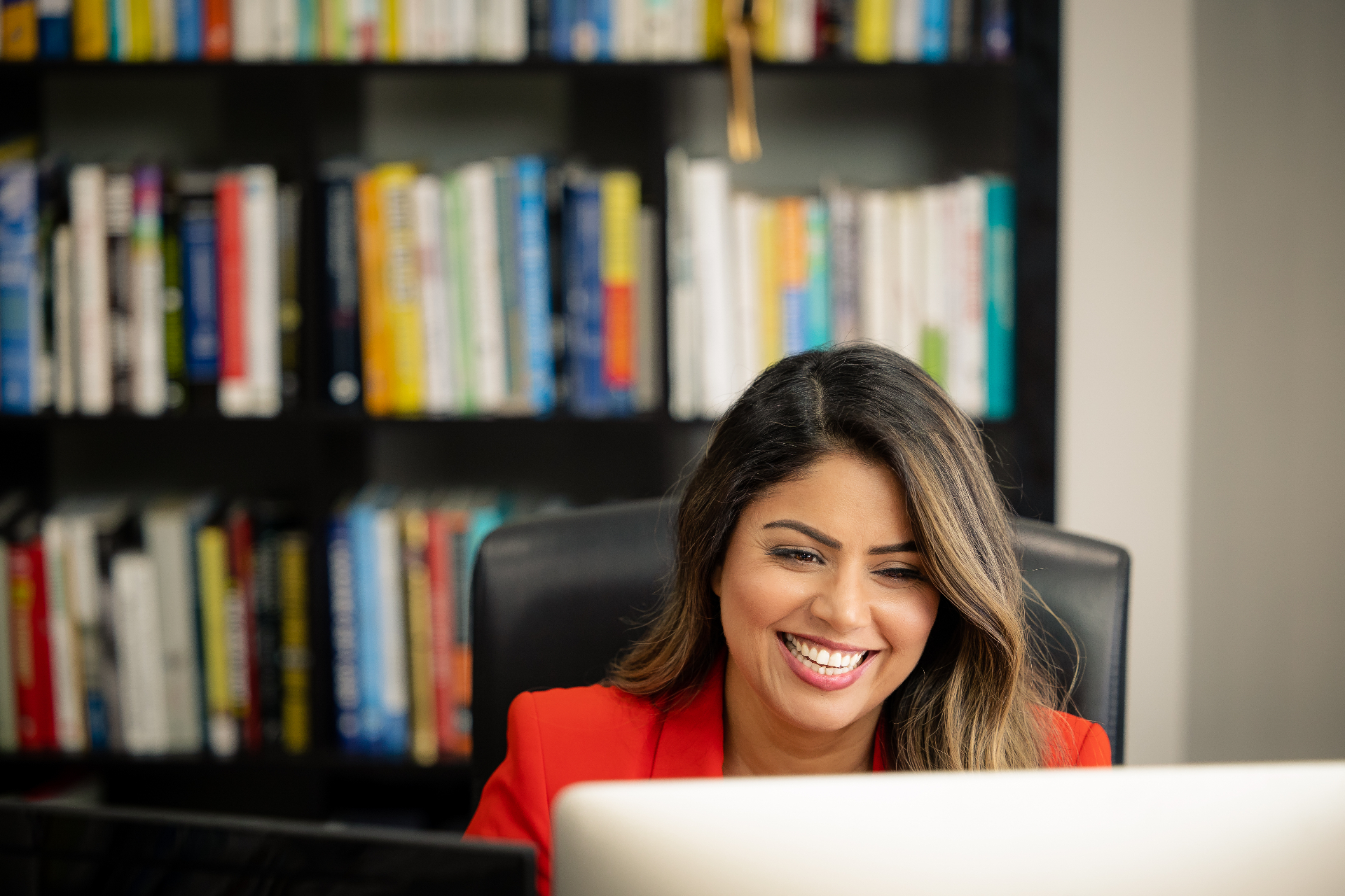 Sandeep working in her office surrounded by leadership and clinical books