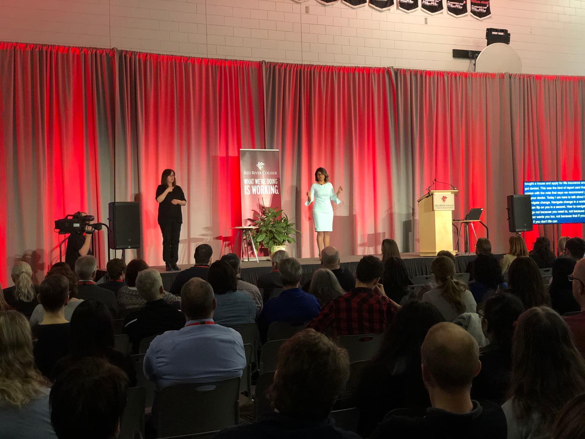 Sandeep Aujla delivering a keynote at Red River College with an ASL interpreter on stage